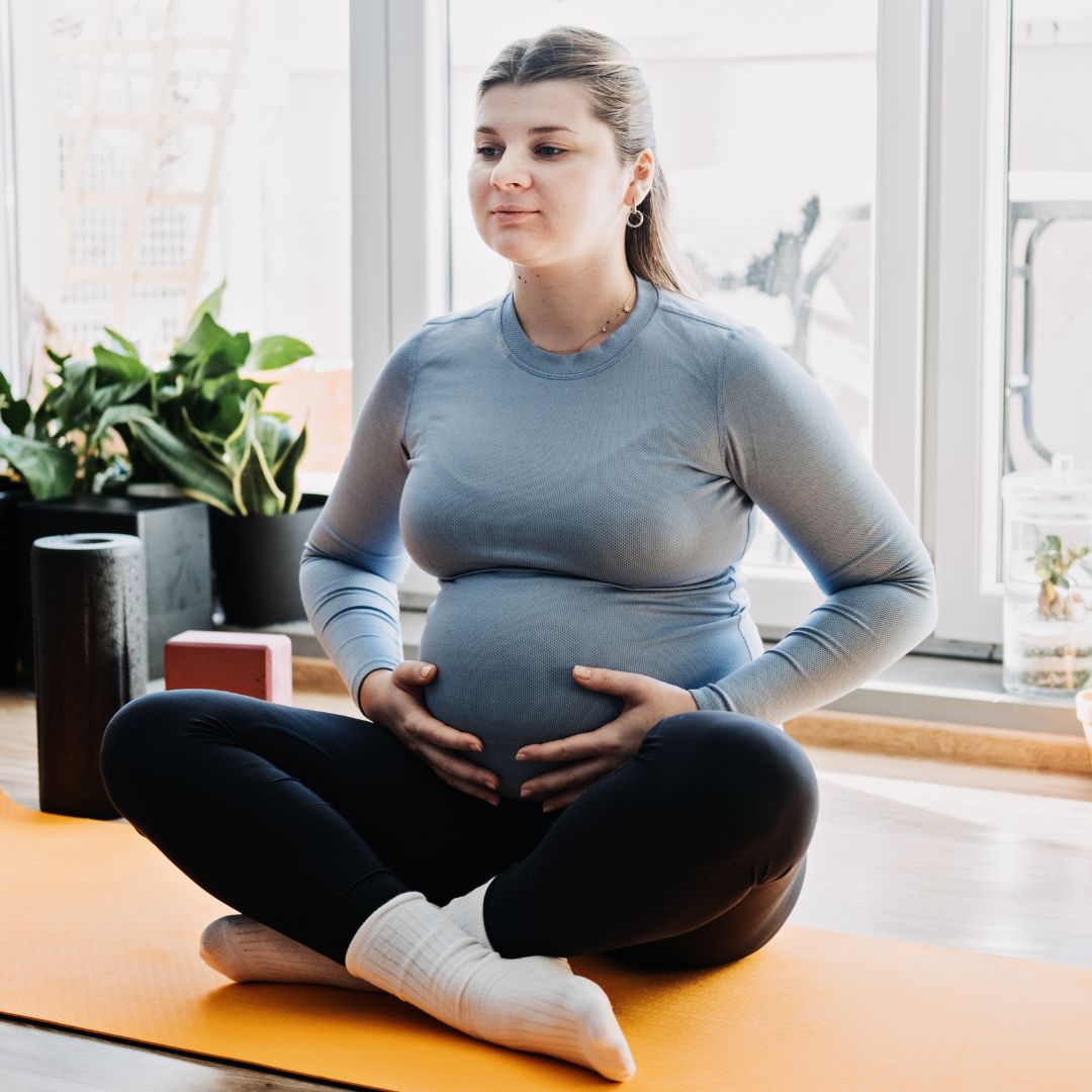 woman in a yoga pose holding her pregnancy belly 